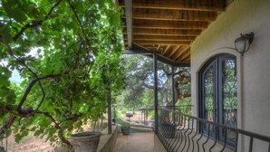 Un espace extérieur abrité, doté d’un chemin en pierre, d’une rambarde en métal et offrant une vue sur un jardin.