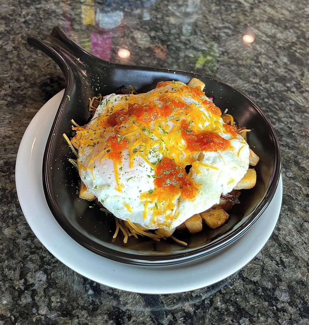 A skillet with a dish containing eggs, cheese, and herbs on a granite countertop.