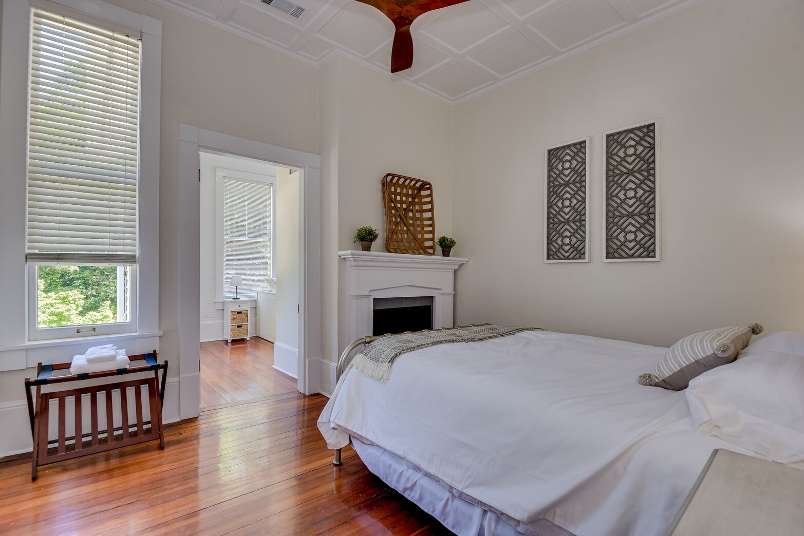 A bedroom with a large bed, a fireplace, and a view of the outdoors through a window.