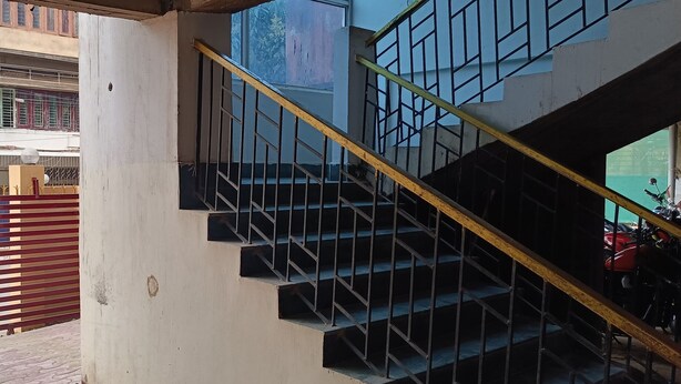 A staircase with metal railings and a yellow handrail, leading to an upper floor. - The Lemon House (Guwahati)