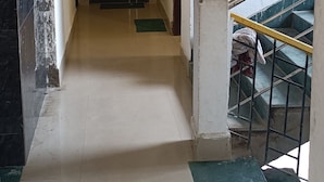 A hallway with a door marked '1', a staircase with a metal railing, and a tiled floor. - The Lemon House (Guwahati)