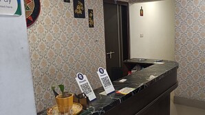 A reception desk with a marble top, a door with a black handle, and a wall with patterned wallpaper. - The Lemon House (Guwahati)
