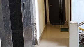 A hallway with a marble wall, a black door, and a tiled floor. - The Lemon House (Guwahati)
