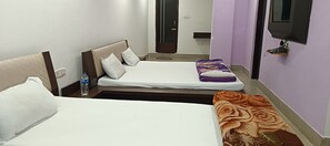 Habitación de hotel con dos camas, un televisor montado en la pared y una botella de agua sobre la mesita de noche.