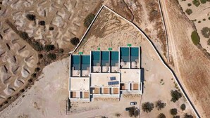 Vue aérienne d’un bâtiment comprenant de nombreuses pièces, des panneaux solaires et un espace de stationnement.