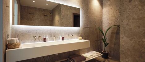 A modern bathroom with a large mirror, a white vanity, and a potted plant.