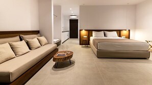 Une chambre d’hôtel moderne, équipée d’un canapé, d’un lit, d’une petite table basse en bois et d’une table de chevet.