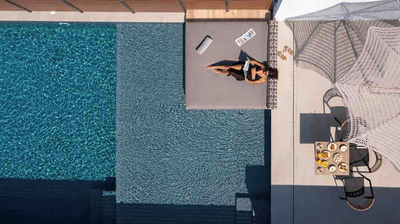An aerial view of a swimming pool area with a lounge chair and a table with food items.