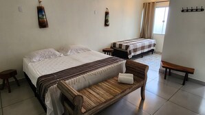 Ein Zimmer mit zwei Betten, einer hölzernen Bank und einem kleinen Tisch.
