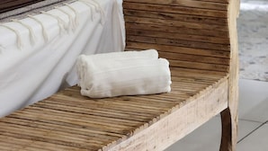 Ein Rattansofa mit weißer Decke und zusammengelegtem Handtuch.