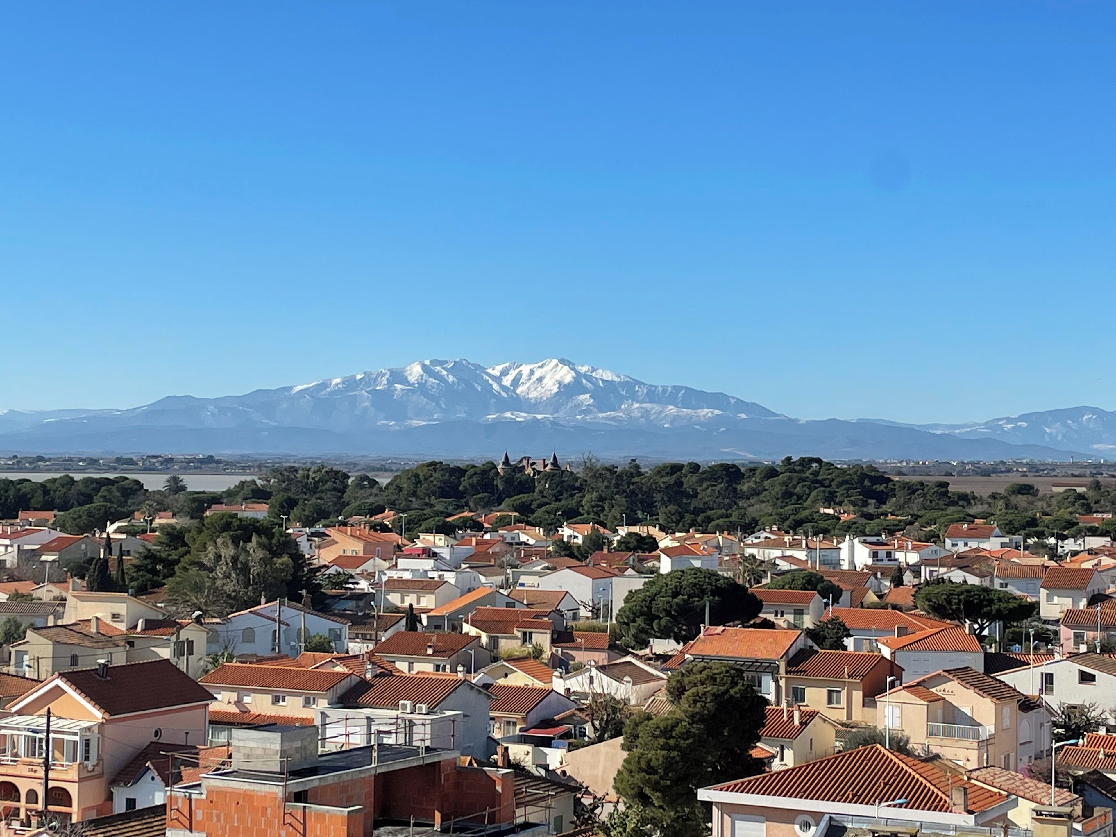 Un poble amb teulades vermelles i una muntanya al fons.