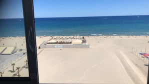 A beach with a sandy shore, a few umbrellas, and a building with a sign reading "Sea-Line".