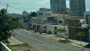 Zona residencial con edificios modernos, cielo despejado y una calle con casas y pequeños árboles.