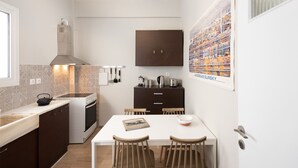 A compact kitchen with a white countertop, dark cabinets, and a dining table with chairs. - Stylish 2 bedroom Apt in Thiseion, large balcony (Athina)