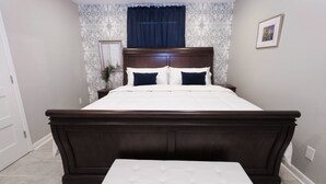 A bedroom with a large bed, a bedside table, a nightstand, a window with curtains, and a framed picture on the wall. - Location, Location, Location! Welcome to a charming 1BR in Uptown New Orleans.  (New Orleans)