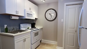 A kitchen with white cabinets, a stove, a microwave, and a clock on the wall. - Location, Location, Location! Welcome to a charming 1BR in Uptown New Orleans.  (New Orleans)