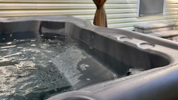 Un jacuzzi con una estructura de madera al fondo.