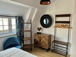 Un dormitorio con cama tipo litera, cómoda, espejo y perchero.