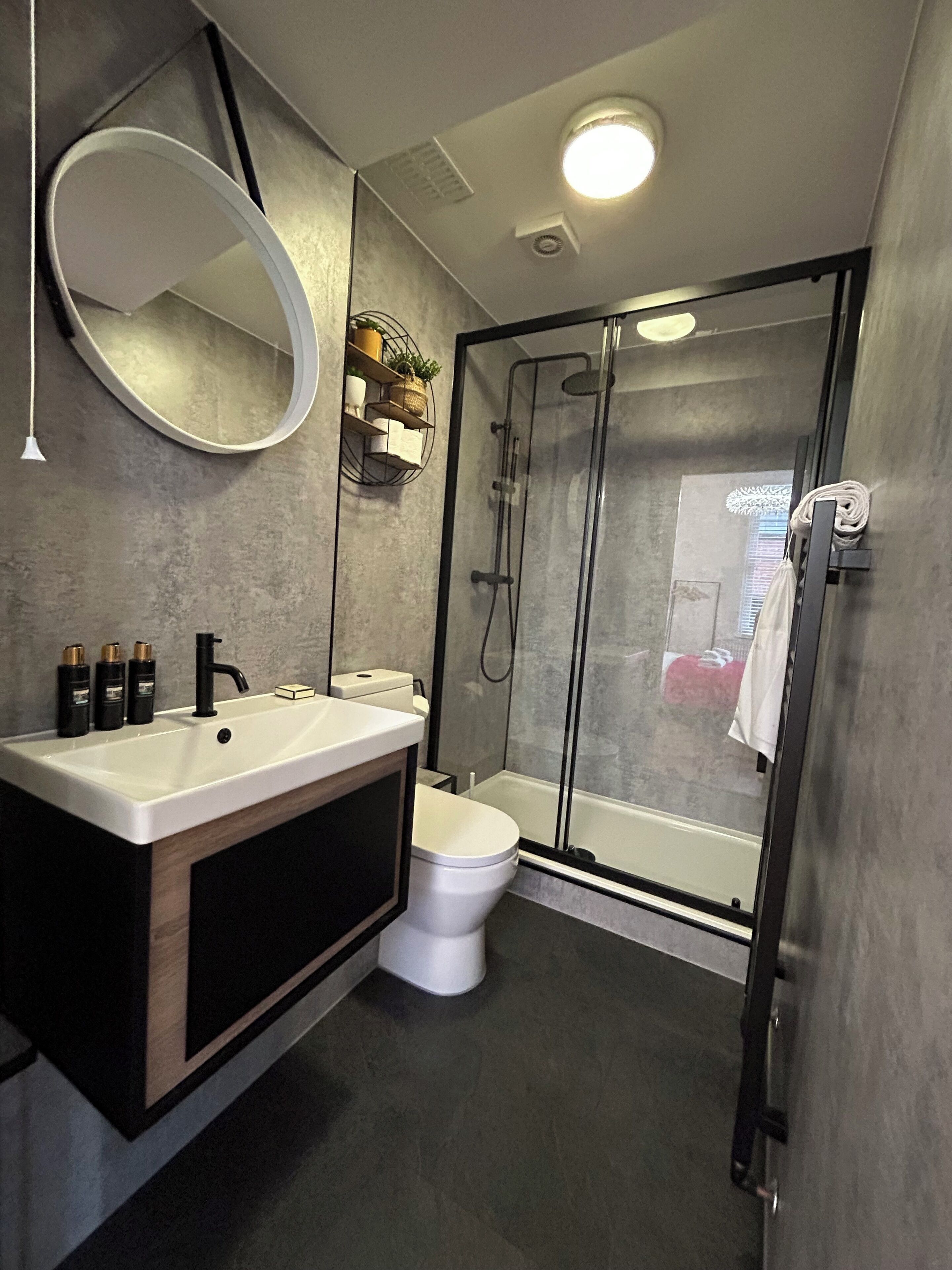 Ein modernes Badezimmer mit großem Spiegel, Waschbecken in Weiß, Toilette und Duschkabine.