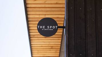 Un letrero circular con el texto 'THE SPOT AT SMITH ROCK' en una pared de madera.