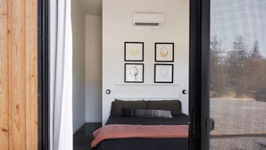 A bedroom with a bed, a window, and four framed artworks on the wall.
