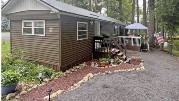Een gelijkvloers vakantiehuisje met veranda, omringd door een grindpad en een aangelegde tuin.