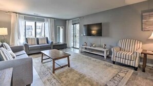 Ein modernes Wohnzimmer mit einem grauen Sofa, einem Holztisch, einem gestreiften Sessel und einem flachbildschirmfernseher an der Wand.