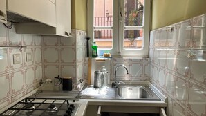 Una cocina con estufa a gas, pileta de acero inoxidable y azulejos decorativos.