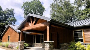 A two-story wooden house with a stone foundation, a covered porch, and a landscaped front yard. - Quiet, country home with luxury amenities. (Dundee)