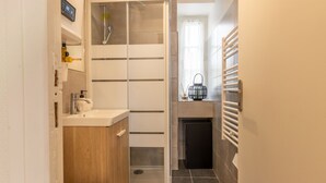 Een kleine badkamer met douche, toilet en wastafel.