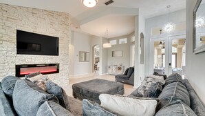 Una sala de estar moderna con pared de piedra, televisor de pantalla plana y sofá modular gris.