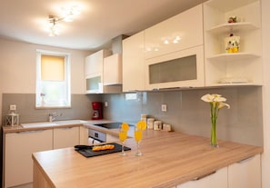 A modern kitchen with white cabinets, a wooden countertop, a coffee maker, and a vase with flowers. - Holiday house Lucy with private pool (Žgaljići (Krk))