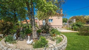 Un jardin avec une fontaine en pierre, des cygnes et un bâtiment en arrière-plan.