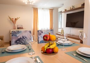 A dining area with a fruit centerpiece, a television, and a window with curtains. - Holiday house Lucy with private pool (Žgaljići (Krk))