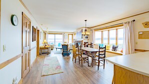Amplia sala de estar con una mesa de comedor, sillas y vistas al exterior.