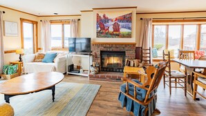 Una sala de estar acogedora con chimenea, televisor y comedor con muebles de madera.