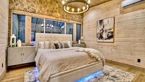 Una camera da letto con un letto grande, un muro in pietra, un lampadario e un quadro.