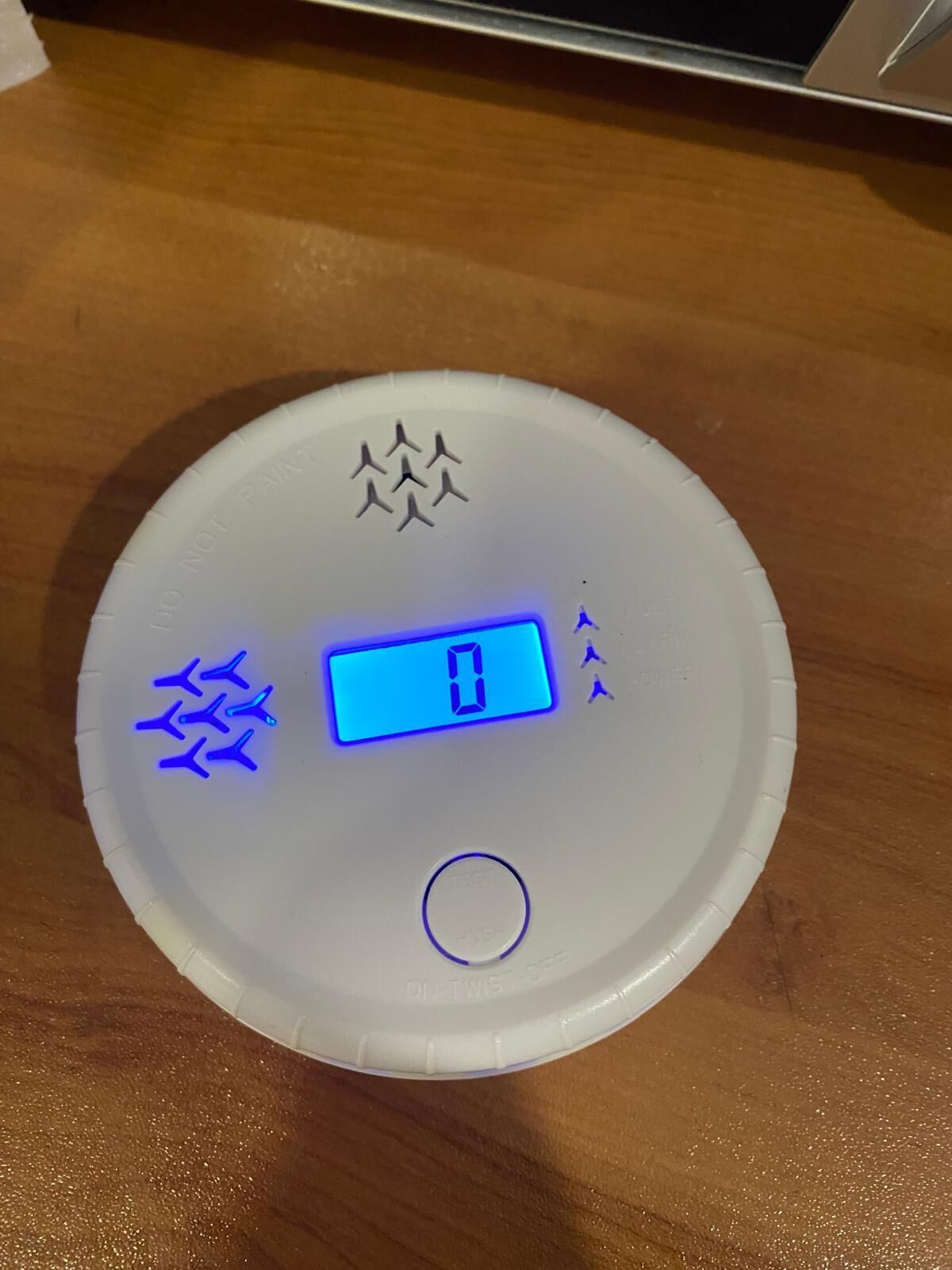Una bilancia digitale con display blu su base bianca, posata su una superficie in legno.