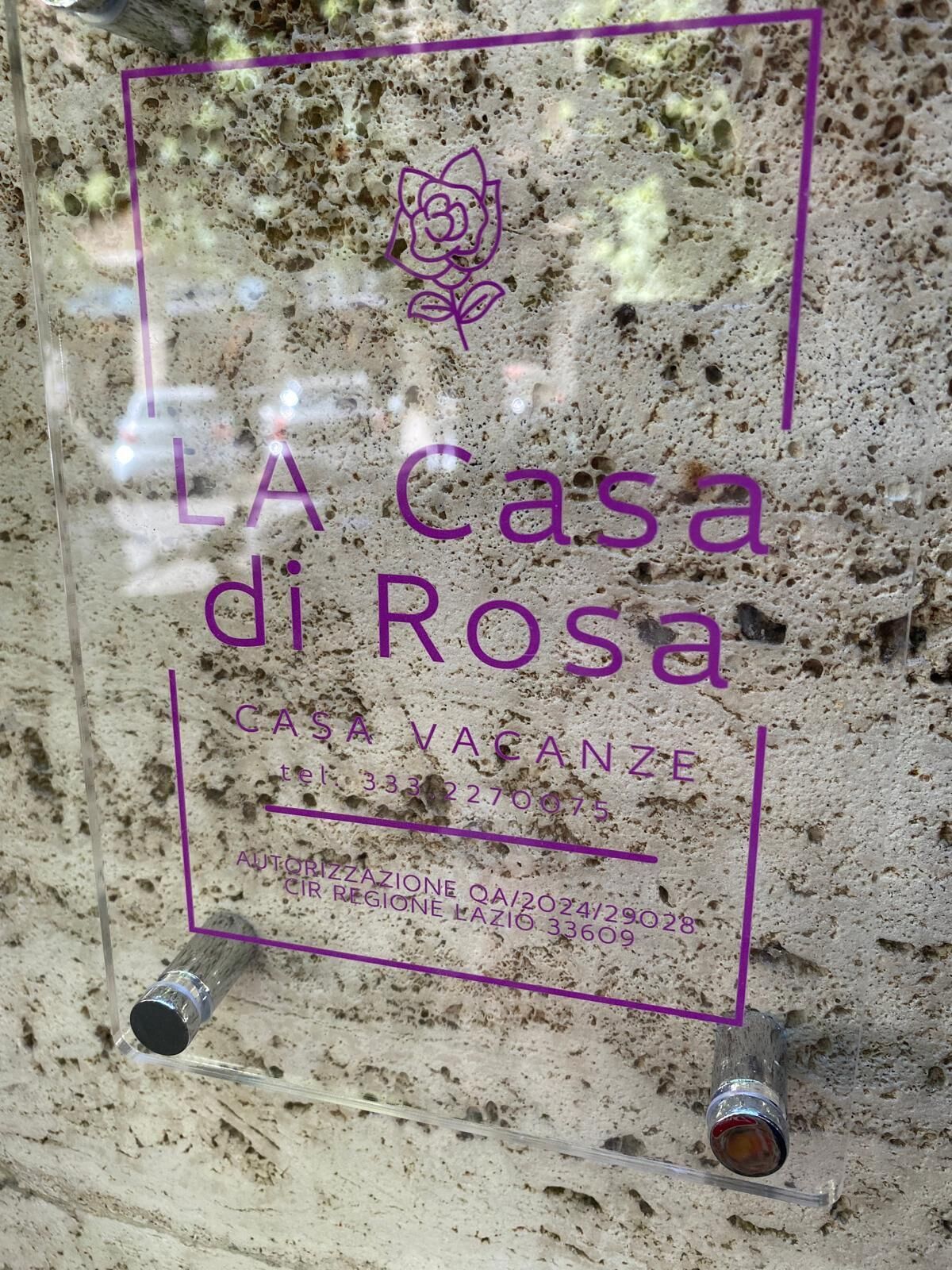 Une enseigne pour « LA Casa di Rosa », avec les coordonnées et un symbole représentant une rose.