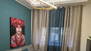 A modern living room with a grey sofa, a white dining table, and a painting on the wall. - Elegant Apartment Near Metro Line B - Luiss Guido Carli (Roma)