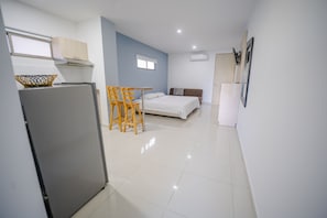 A compact room with a bed, a small table, and a refrigerator.