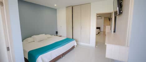 A modern bedroom with a large bed, a wardrobe, and a TV mounted on the wall.