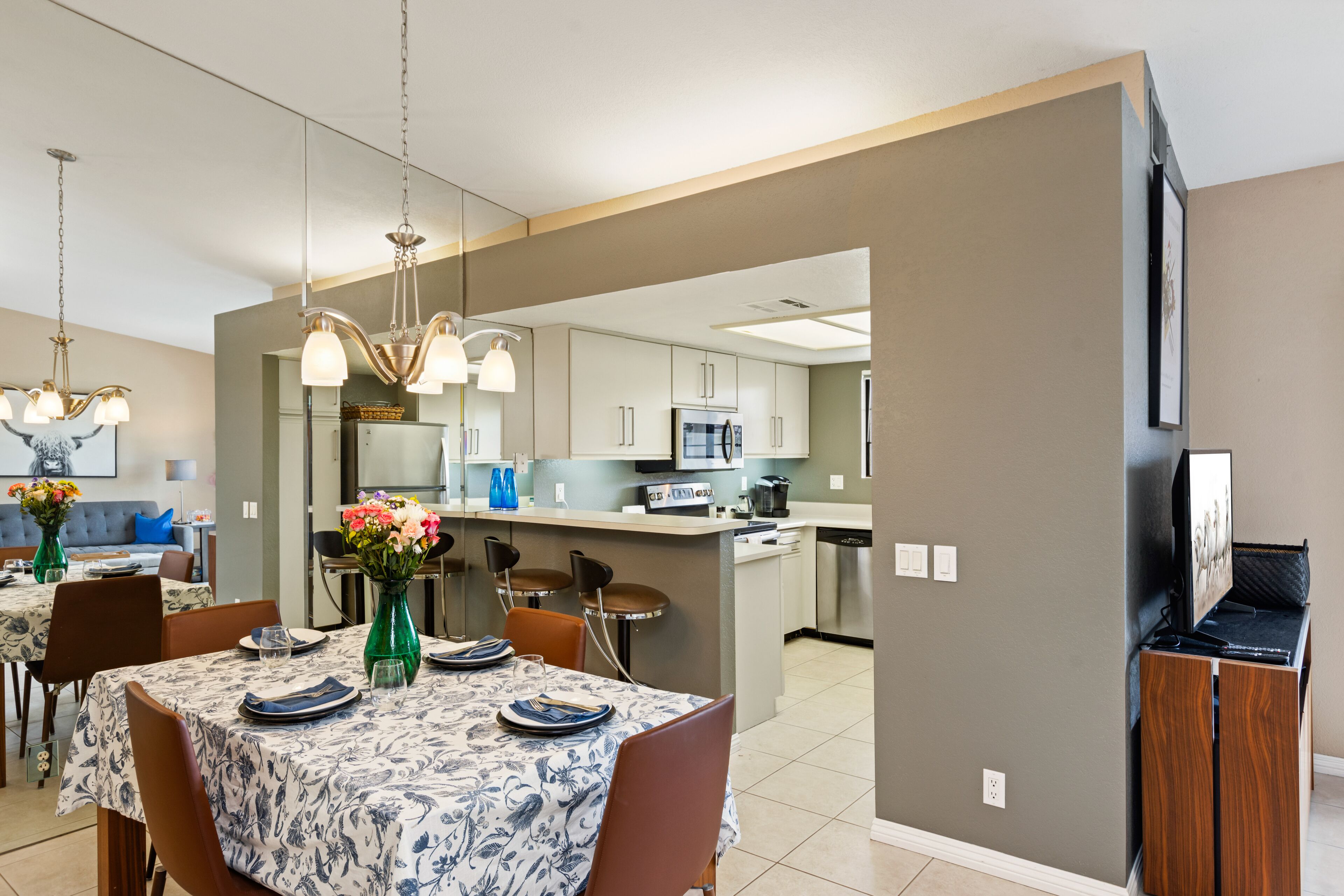 A modern kitchen with white cabinets, a central island, and a dining area with a table set for four.