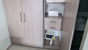Une armoire avec plusieurs étagères et tiroirs, une serviette blanche et une petite boîte blanche posée sur le sol.