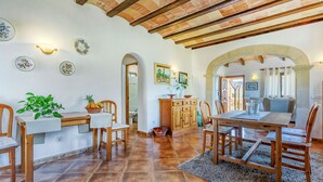 A spacious dining area with wooden furniture, a tiled floor, and a high ceiling with exposed beams. - Can Juanito by dracmallorca (Cala Llombards)