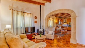 A living room with a sofa, TV, and a dining area with chairs and a table. - Can Juanito by dracmallorca (Cala Llombards)