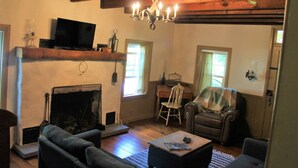 A cozy living room with a fireplace, a television, and comfortable seating. - Historic Farmhouse in Chester County (Downingtown)