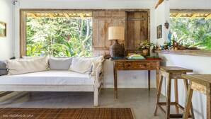 Una habitación con una cama de madera, un escritorio con una lámpara y vistas a exuberante vegetación.