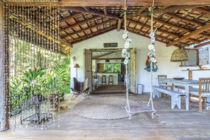 A rustic wooden interior with a dining area, hanging decorations, and a view into the kitchen. - Casas da Lia (Porto Seguro)