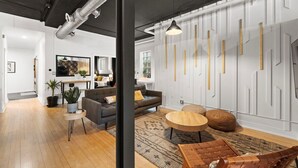 A modern living room with a grey sofa, a round wooden coffee table, and a patterned rug. - The Lincoln Square Hideaway (Chicago)
